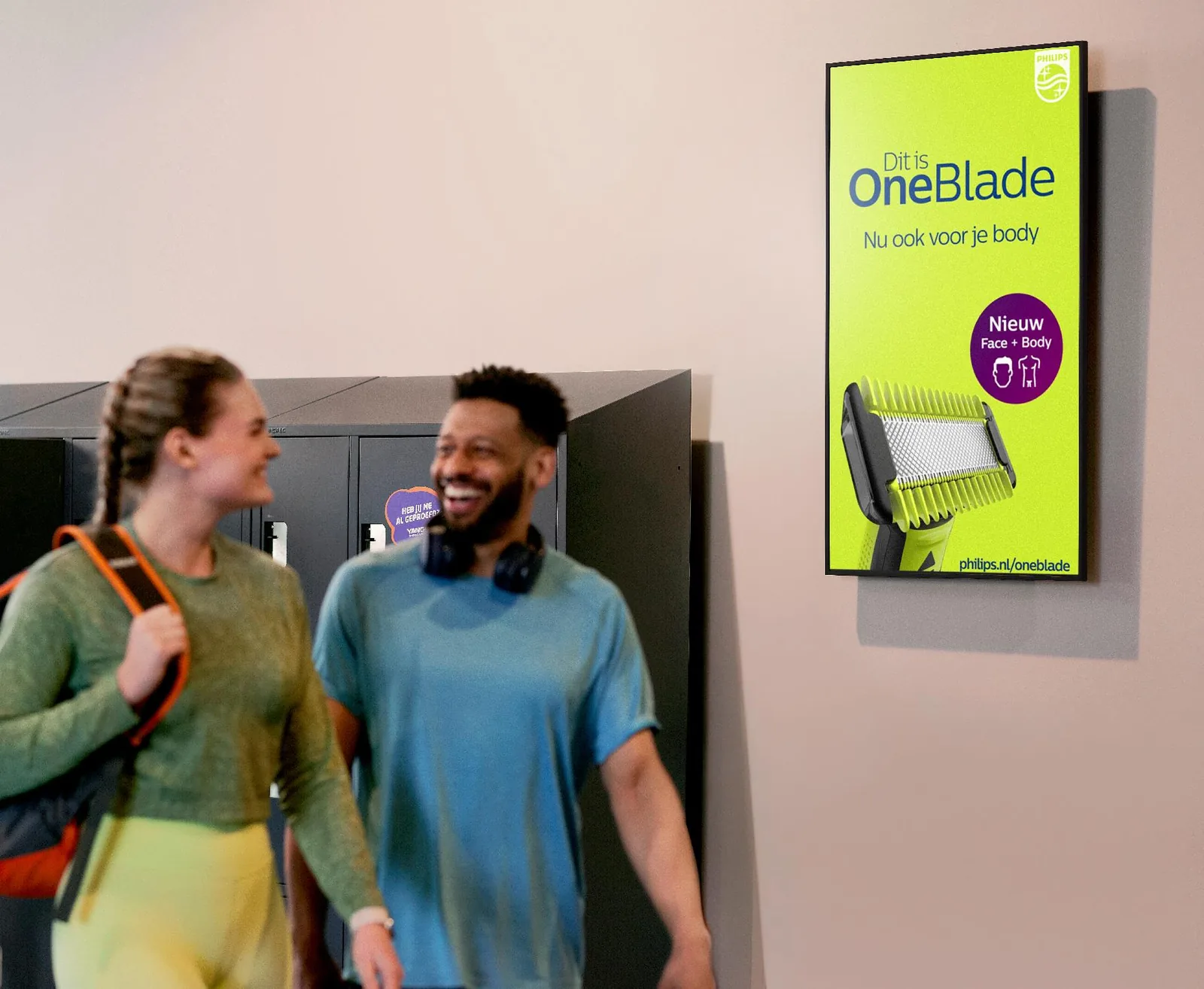 Écran publicitaire fixé au mur de la salle, sur le passage des adhérents